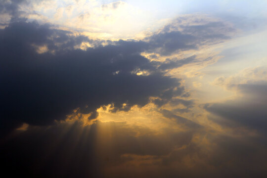 yellow sun rays coming out from black clouds © rajiv