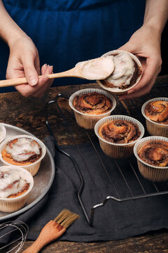 Preparation of homemade cakes. The girl spreads the cream on the pastry. Cinnabon. Rustic