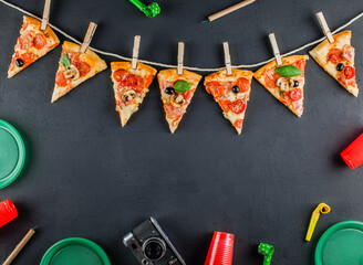 Slices of pizza in the form of a garland with the attributes of a party. Pizza slices on a gray...