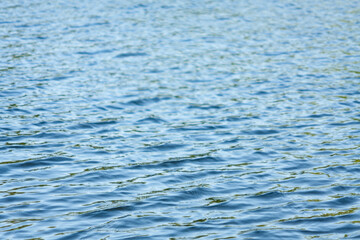 Background of water. Water surface with small waves on the river close-up. Water surface on a clear day