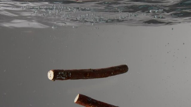 three licorice cticks falling into the water Underwater slow motion from 120 fps