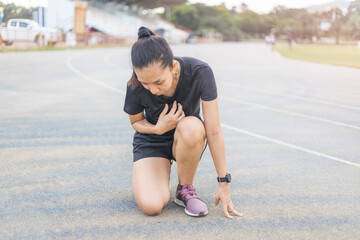 Women are tired after running hard on the running track. She is touching on the heart area.