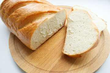 a loaf of white bread is sliced. White bread on a wooden board, on a light background. Bread texture, homemade cakes, cooking, breakfast, bakery.