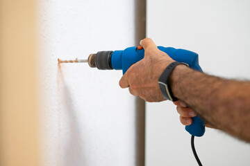 Carpenter drilling the wall with a drill. Drilling a white wall. Drill concept.