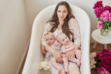 Mother and twins in milk bath. Happy family. Maternity and parenthood. Children Protection Day. Mother's day card. Congratulation on Women's Day. Newborn Kids Boy and Girl