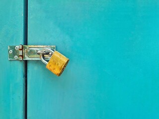 Rusty golden lock with locked blue metal door texture background with space