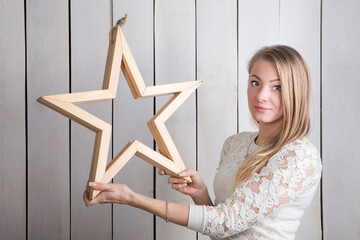 closeup young blonde woman holding small wodden star shaped decoration