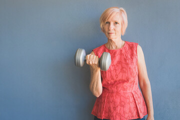 Senior lady lifting weights at home to stay fit