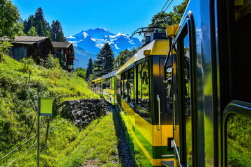 Beautiful scenery with yellow and green train - Bernese Highlands Railway, from Lauterbrunnen village to Grindelwald , Jungfrau region, Bernese Oberland, Switzerland