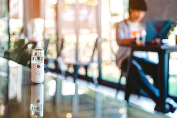 Alcohol nano mist sprayer for hand cleaning to prevent the spread of the corona virus (Covid-19) placed on the table to serve customers before buying in the coffee shop. Modern health technology.
