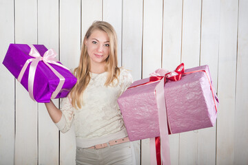 young pretty blonde woman looks at camera holding in hands two large gift boxes