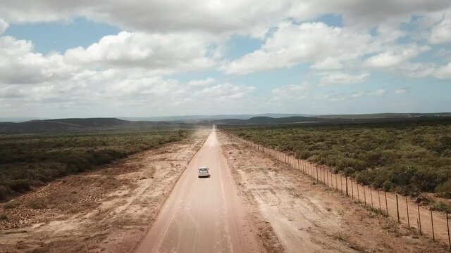 A car on a dirt road leading to the Addo Elephant National Park, near Port Elizabeth from a drone