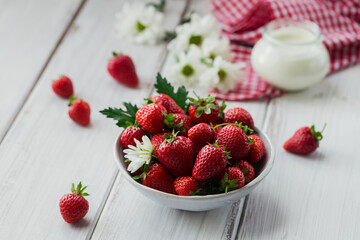 Healthy breakfast with ripe sweet berries and dairy product. Fresh strawberries in ceramic bowl and natural bio yogurt on white rustic table