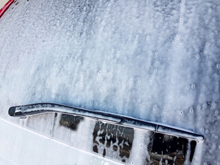 rear window with a wiper blade coated with detergent active foam with bubbles for washing a car, closeup vehicle side view nobody with copy space.