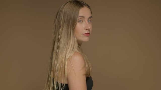 profile portrait of young blonde model with long straight hair in studio turned to the camera and watching to the camera