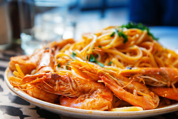 Italian pasta and big shrimps with tomato sauce served in white plate for a delicious meal