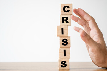 Hand protect wooden cubes block which print screen crisis wording. Financial and economic crisis concept.