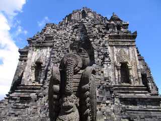 Fototapeta premium Close up vertical focus detail of Gate stone carved statue with Kalasan Temple (Candi) as the background. Buddhist temple at Sleman, Yogyakarta, Central Java, Indonesia. 