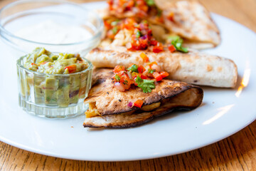 Delicious Mexican quesallidas made with chicken, tomato pieces and served with guacamole sauce.