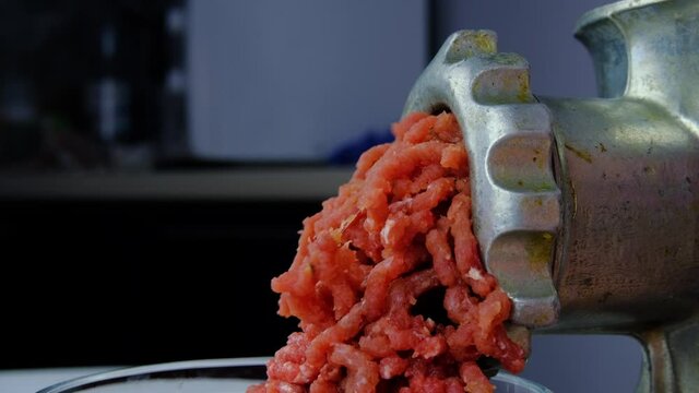 Cooking minced meat with a manual meat grinder. Close-up of front part of mincing-machine with mincemeat in. Showing the forcemeat process.