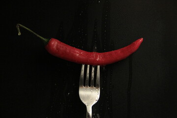 red pepper in a fork on a black background