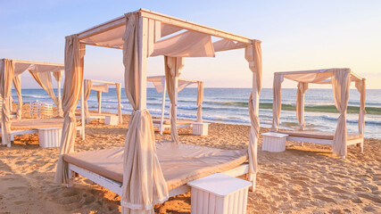 Coastal landscape - view of the sandy seashore with beach gazebos. Beach holiday concept