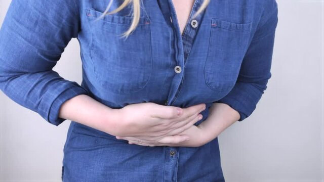 A woman holds on to his stomach. Pain in the abdominal cavity. The concept of diseases of the stomach and digestive system