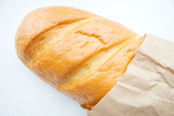 A loaf of fresh white bread, ciabatta with a crust, in a paper, craft bag, on a light background. The texture of the bread, pastries, cooking, breakfast. Bread in environmental packaging, paper bag. 