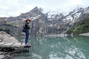 Naklejka premium An Asian woman by the lake. Snow capped mountain reflection on water.
