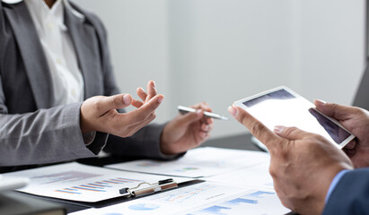 Asian business men and women are brainstorming and analyzing corporate financial graph data in the office.