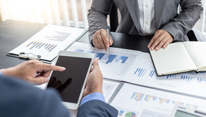 Asian business men and women are brainstorming and analyzing corporate financial graph data in the office.