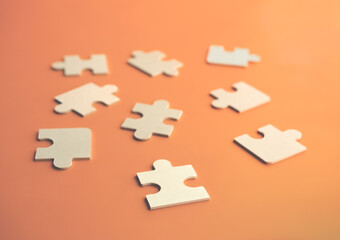 Close-up puzzles lying on an orange background. A concept of large wooden puzzles. Soft focus on the front puzzle. Order, Puzzle, Jigsaw Piece, Connection, Leisure Games. Blurred background