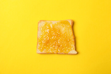 Toast with orange jam on yellow background, close up