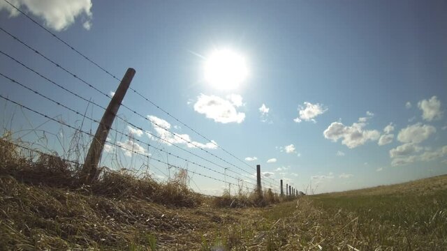 Rotating time lapse of a barbed wire fence where livestock graze on a farm in Alberta Canada.

