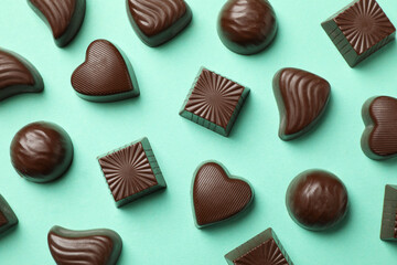 Tasty chocolate candies on mint background, top view