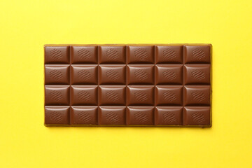 Tasty chocolate bar on yellow background. Sweet food