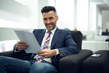 Smiling professional businessman dressed in formal trendy outfit happy to signing beneficial...
