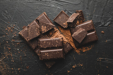 Tasty chocolate and powder on black background