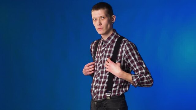 skinhead man stands and takes black suspenders