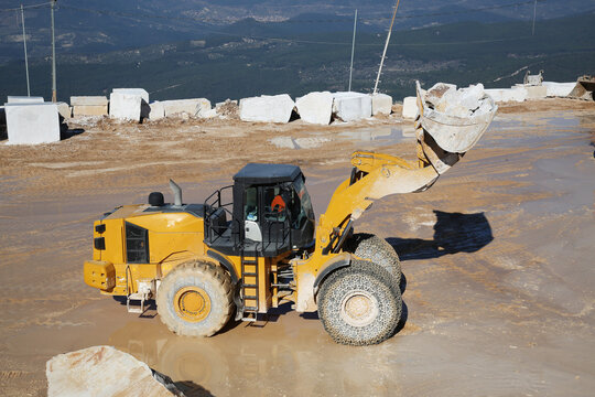 a big whell loader working in marble quarry. A loader truck loading to dumper
