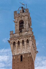 Detail of Mangia Tower and its tabernacle, the civic tower of the town hall of Siena in Piazza del campo. Tuscany, Italy