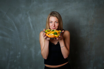 closeup young blond woman looks at camera showing dish with citrus fruit slices