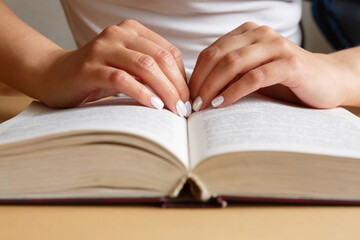 A woman is reading a book. Hands are holding a book. Beautiful manicure