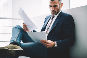 Successful mana lawyer dressed in elegant formal outfit checking financial documentation and...