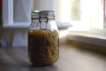 Glass jar with pasta in the kitchen. Selective focus.