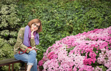 Beautiful lady wearing a nice scarf. She sitting in the floral garden and posing with happiness motion