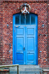 Blaue Holztür in rot verklinkertem Haus
