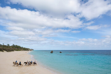 Fototapeta na wymiar Bermuda beach with horseback riders in the distance