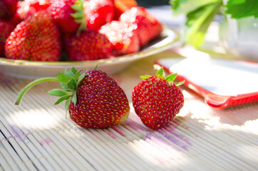 Freshly cut strawberries on a wooden cutting board and delicious strawberries in a glass bowl on wooden table. Season's fruit. Healthy food. Wooden background. Ecological and organic food. Agriculture