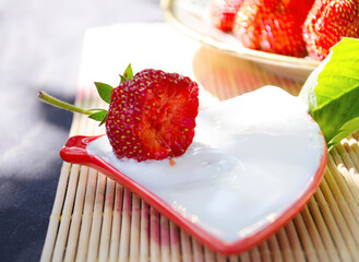Freshly cut strawberries on a wooden cutting board and delicious strawberries in a glass bowl on wooden table. Season's fruit. Healthy food. Wooden background. Ecological and organic food. Agriculture